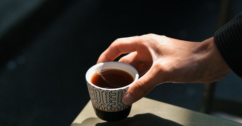 Personalize - A person holding a cup of coffee on a table