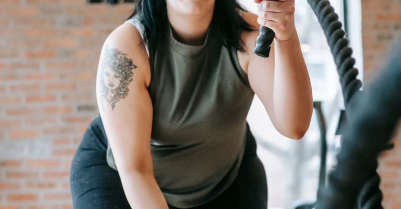 Functionality - Low angle of concentrated female in sportswear exercising with heavy battle ropes during intense functional training